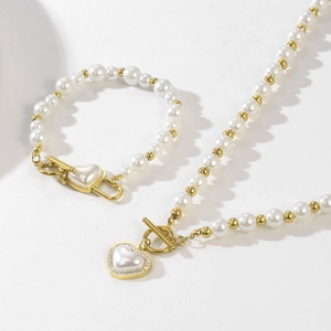 Detail of gold pearl jewelry set with heart-shaped mother-of-pearl pendants and OT buckle