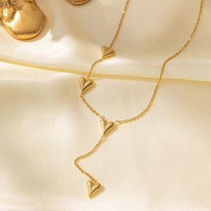 Elegant gold titanium heart necklace with four 3D pendants on soft silk background