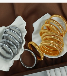 Detail view of gold and silver textured stretch snake bone bracelets on shell tray