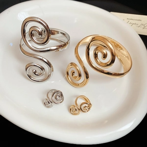 Macro shot of gold and silver spiral metal bracelets and rings on a white tray