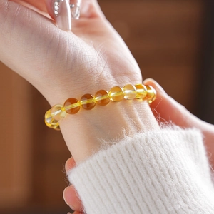 Detailed view of translucent yellow citrine beaded bracelet on a woman wrist