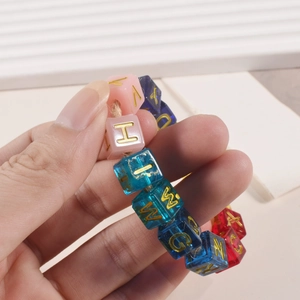 Close-up of colorful resin alphabet bead bracelet with golden letters on white stand