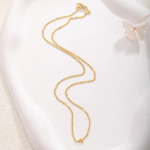 Detail of a 18k gold plated twist chain necklace with star motifs on a stone tray