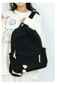 Detail eines schwarzen Cord-Rucksacks mit Mehrfachtaschendesign und Bärenanhängern