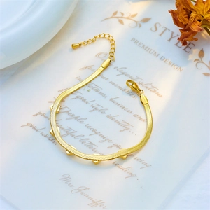 Minimalist gold snake chain bracelet with sparkling heart charms on artistic background