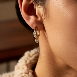 Vue détaillée d'une boucle d'oreille fleur en zircon doré portée sur le lobe de l'oreille