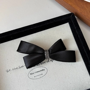 Detailed macro view of black satin bow hair claw clip with shimmering rhinestone center