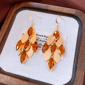 Detailed view of vintage 18K gold-plated teardrop earrings on a wooden texture background