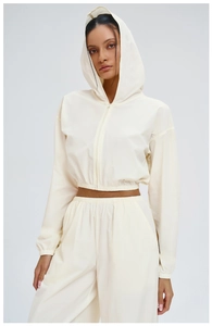 Detail view of cream-colored hooded cropped windbreaker jacket and matching joggers