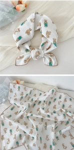 Detail of white cotton linen scarf featuring cartoon bear patterns and brown piping edges