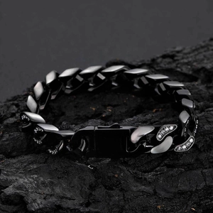 Close-up of 12mm black iced-out Cuban link chain bracelet on a dark volcanic rock surface