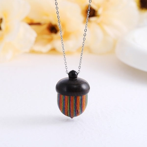 Macro detail of the acorn-shaped wood and metal pendant on a delicate chain