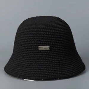 Detail of hand-woven crochet texture and rectangular metal logo on black cloche hat