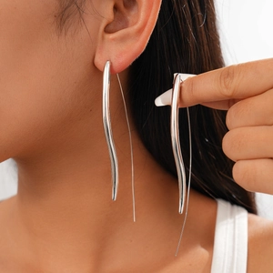 Polished silver wave drop earrings on a model with minimalist metallic finish