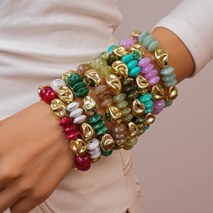 Close-up of bohemian stacked beaded bracelets with colorful resin and irregular gold beads