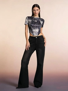 Dettaglio dei jeans svasati con orlo a taglio vivo e crop top con stampa marmorizzata
