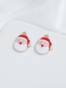 Detailed close-up of two Santa Claus enamel charms on white satin fabric