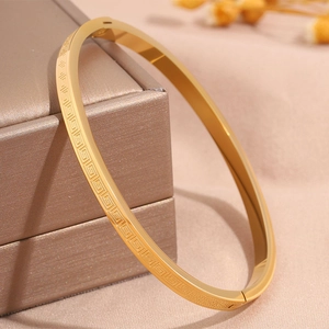Detail of gold titanium steel bangle with Greek key pattern on a jewelry box