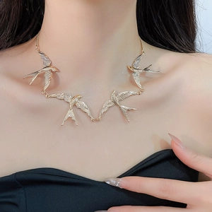 Detail der goldenen Schwalbenvogel-Halskette im Vintage-Stil am Model-Schlüsselbein