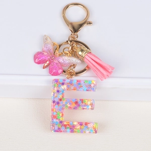 Detail of resin letter E keychain with colorful sequins, pink butterfly and tassel charm