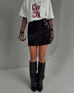 Détail du t-shirt en coton blanc avec lettrage GIN CIN rouge et jupe noire à paillettes