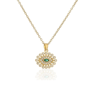 Detailed close-up of golden evil eye pendant with green stone and sparkling zircon stones