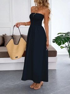 Detail of a dark blue strapless maxi dress styled with a large woven tote bag