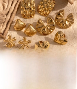 Detail of gold titanium steel earrings with shell and floral designs in vacuum plating