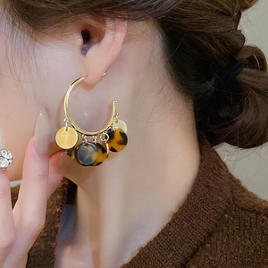 Detail of vintage leopard print hoop earrings with golden metallic and tortoiseshell resin discs