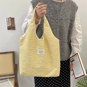 Detail of yellow woven tote bag with colorful thread accents and brand label