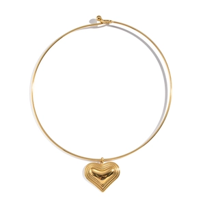 Detailed view of a 18K gold-plated heart pendant on a rigid metal collar necklace