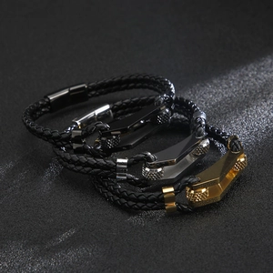 Detailed close-up of three layered braided leather bracelets with gold, silver and black clasps