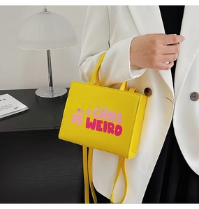 Detail of trendy yellow PU leather shoulder bag featuring pink art typography print