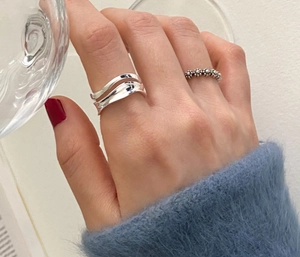 Detail of minimalist 925 silver wave ring and beaded flower ring on model hand