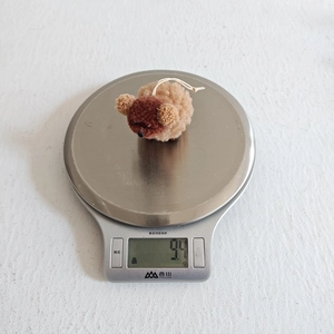 Close-up of lightweight plush dog ornament weighing 9.4g on a digital scale