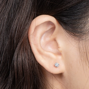 Macro shot of a four-prong set moissanite stud earring on ear in 925 sterling silver