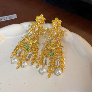 Macro detail of vintage bird and flower earrings with rhinestones and pearl drops