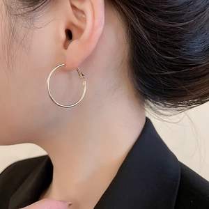 Gros plan sur une boucle d'oreille créole argentée ronde portée par un mannequin