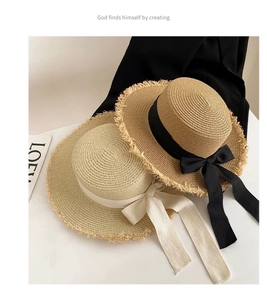 Detail of frayed edge boater hat with ribbon bow and textured straw weave pattern