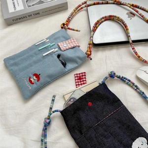 Detail of embroidered corduroy and denim crossbody bags with colorful woven straps