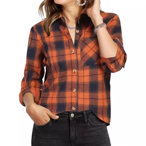 Detail of classic orange and black plaid shirt featuring a chest pocket and buttoned cuffs