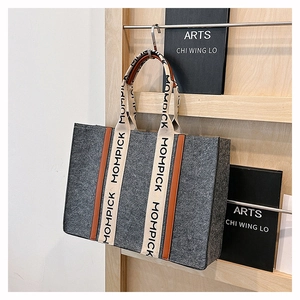 Detail of grey felt tote bag with brown trim and MOMPICK branded shoulder straps