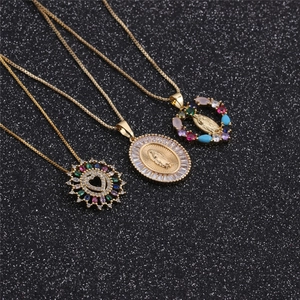 Three gold heart and religious pendants with colorful zircons on a black background