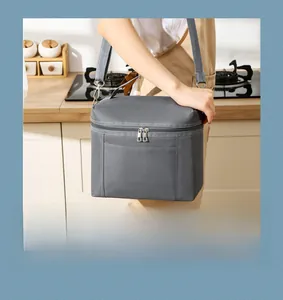 Grey insulated lunch bag with adjustable shoulder strap shown in a kitchen setting