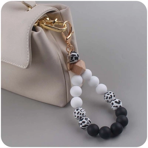 Detail of DIY silicone beaded keychain with leopard print beads on a beige handbag