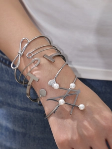 Close-up of silver bow and pearl geometric bracelets on model wrist for daily style