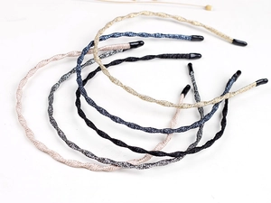 Detail showing five metallic glitter wavy headbands in gold, silver, blue, pink, and black