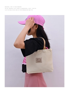 Detail of canvas tote bag with embroidered bear logo and comfortable carry handles
