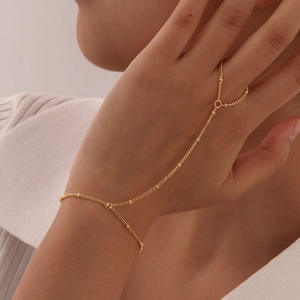Detail of 18K gold-plated double-layer slave bracelet on hand with sleek finger ring chain