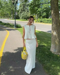 Detail of white pleated sleeveless top and matching maxi skirt with yellow woven bag